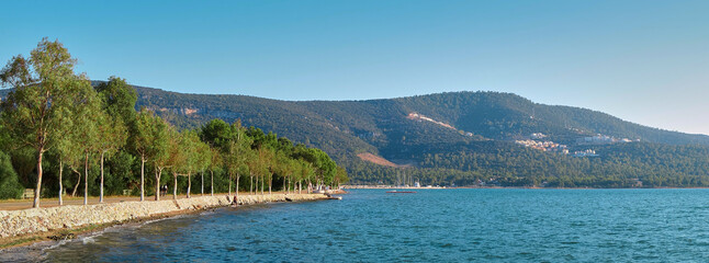 Panorama of the coast and the sea in the village of Akbuk in Turkey. Mountains covered with forest in the background
