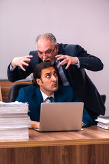 Old male employer and young male assistant in bullying concept