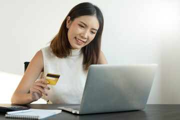 Obraz premium Young Asian woman using credit card for online shopping in coworking space, technology money wallet and online payment concept, credit card mockup