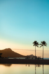 Silhouetted People and Palm Trees at Sunrise At a Beach Front Tourist Resort in Hawaii