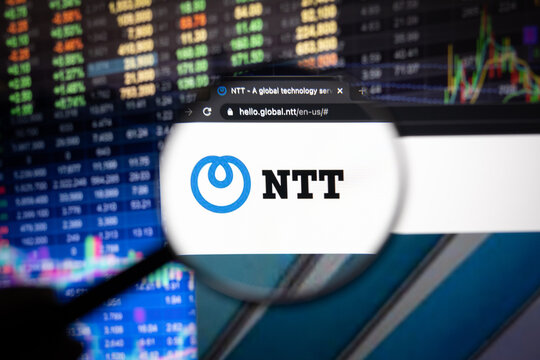 NTT company logo on a website with blurry stock market developments in the background, seen on a computer screen through a magnifying glass