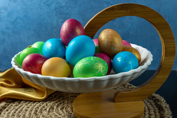 The plate is on the table with colored chicken eggs. On a blue background.
