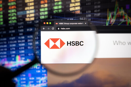 HSBC company logo on a website with blurry stock market developments in the background, seen on a computer screen through a magnifying glass