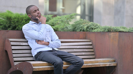 Pensive Young African Man Sitting on Bench and Thinking 