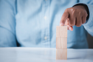 Hand holding wooden block cubes on table, business idea creative concept structure wooden block development leadership abstract background.