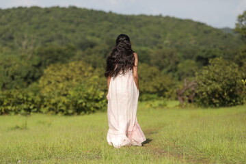 young woman in a green hill location in a white dress 