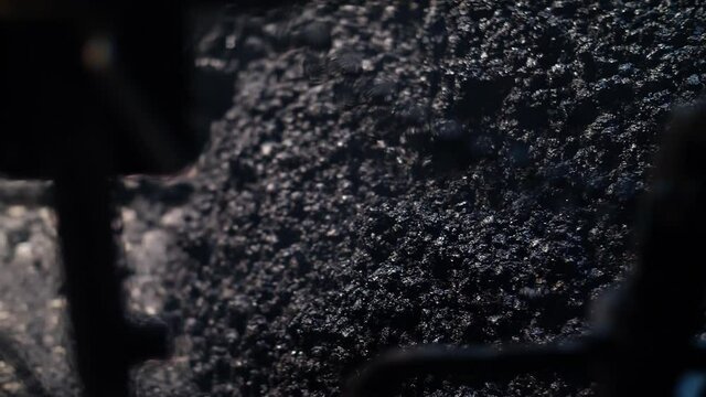 Close-up of fresh asphalt mix. An asphalt paver is placing asphalt mixture on the road. Road repair, new road construction.