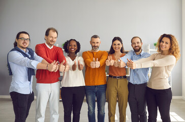 Group of interracial people showing raised thumbs on camera as a gesture of recommendation or a good choice. Multicultural team demonstrates satisfaction and gives a positive response.