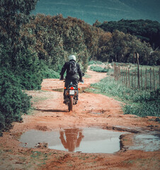 Back view of a biker riding on a dirt road