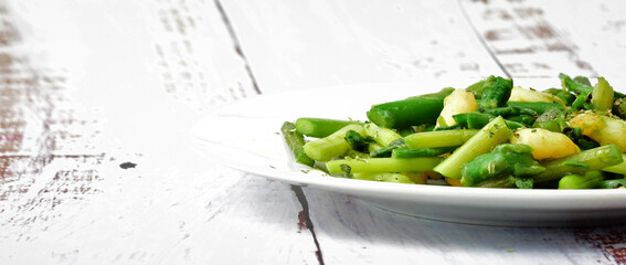 Asparagus with prawns, a touch of spices, oregano and olive oil, served on a white plate. Copy space.