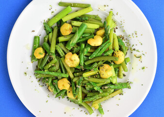 Zenith view. Asparagus with prawns,, a touch of spices, oregano and olive oil, served on a white plate on a blue background. 