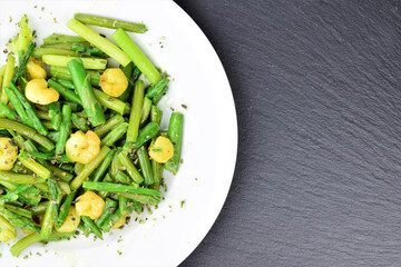 Zenith view. Plate of asparagus with prawns, a touch of spices and olive oil, slate stone background. Copy space.