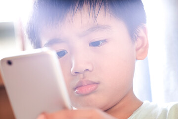 Closeup of young kid using smartphone. Outdoors with lens flare.