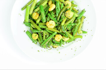 Asparagus with prawns, a touch of spices and olive oil, white background. Zenith view. Copy space.