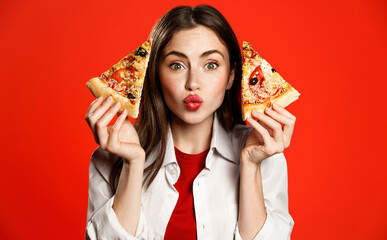 Cute girl shows two slices of delicious pizza takeaway, making kissing face, loves pizzeria...