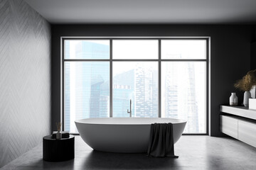 Dark bathroom interior with bathtub, table with towels, windows on skyscrapers