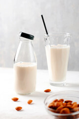 In a glass bottle and glass, gluten-free almond milk on a light background. Organic natural vegetarian drink. Health concept. Vertical position