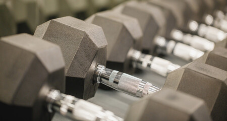 Rows of black dumbbells in the workout gym in high resolution and urban style.