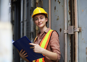 Young Engineers standing in the shipping yard tracking the cargo inventory and checking container box for safety.