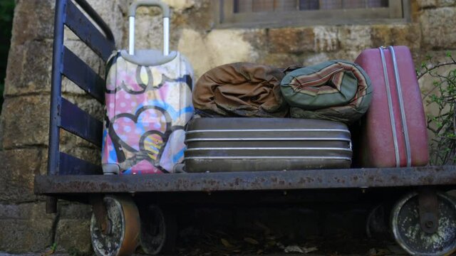 Luggage on old platform trolley in front of rustic wall