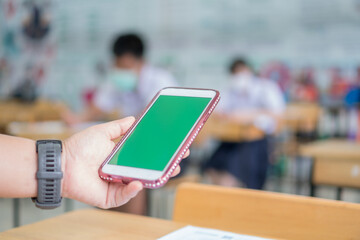 Mock up green screen smart phone, Application digital smartphone on exam testroom while Students school wear face mask learning project searching app in online classroom learners in modern technology