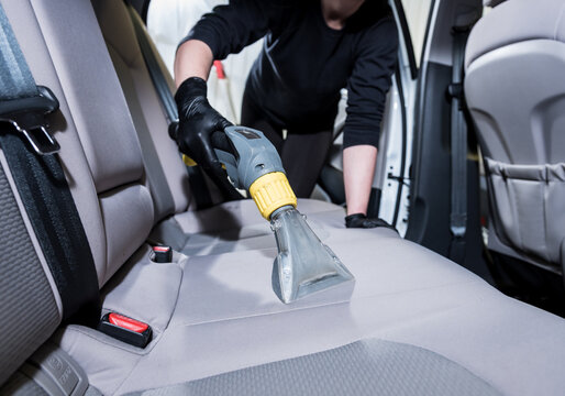 Worker cleans car interior with vacuum cleaner