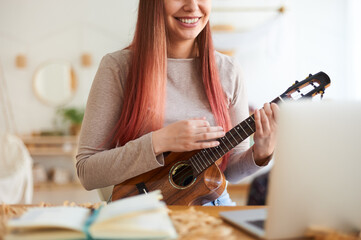 Fototapeta premium Faceless young woman playing ukulele. Online music tuition.