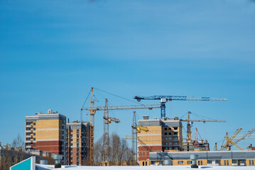 construction tower cranes build monolithic frame houses and brick houses against the sky in the city