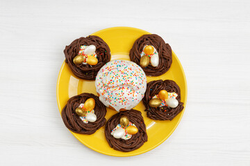 Homemade Easter cake decorated with candies in the form of Easter eggs on white wooden table. Top view.