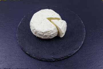 Soft Adyghe cheese on black slate background