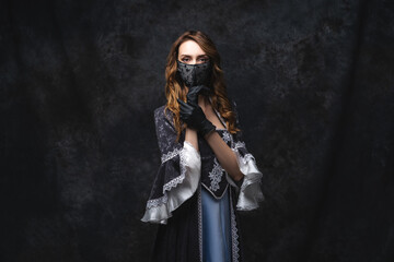 Fototapeta premium Beautiful woman in renaissance dress, face mask and gloves on abstract dark background, coronavirus, covid-19 protection concept