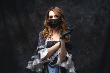 Naklejka premium Beautiful woman in renaissance dress, face mask and gloves on abstract dark background, coronavirus, covid-19 protection concept