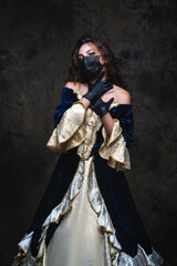 Obraz premium Beautiful woman in renaissance dress, face mask and gloves on abstract dark background, coronavirus, covid-19 protection concept