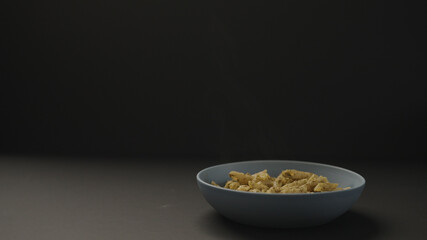 hot pesto penne in blue bowl on black background