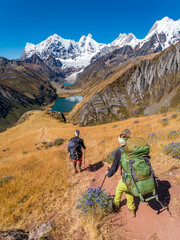 Fototapeta premium Girl backpackers hiking towards amazing Jahuacocha lakes at Huayhuash circuit, Cordillera Huayhuash, Peru, South America