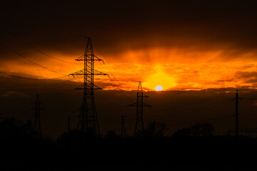 Fototapeta na wymiar High voltage power line at sunset. Silhouettes of the metal pillars