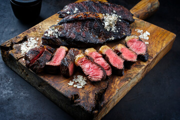 Traditional barbecue dry aged wagyu Brazilian picanha steaks from the sirloin cap of rump beef sliced and served as close-up on a rustic wooden board