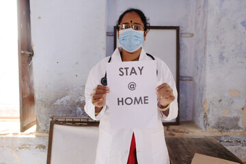 Indian medical worker holding a poster with the message "stay home" during the covid-19 pandemic