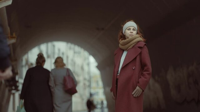 sad girl standing on a city avenue among people