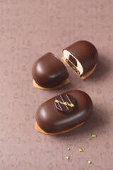 Contemporary Mini Mousse Cakes, covered in chocolate, decorated with chocolate elements, on a brown background.