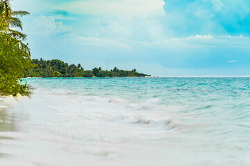 Panoramic view of a tropical beach with palm trees, turquoise waters and blue sky in the Maldives, Indian Ocean