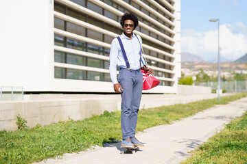 Black businessman riding skateboard near office building.