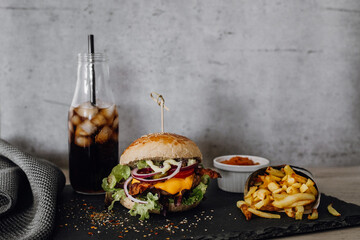 Hamburger, köstlich, saftiger Bacon Burger mit Pommes, Dip und Cola auf Schieferplatte