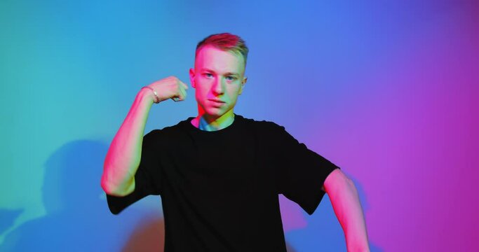 4k video of modern guy cool dancing to music. Free creativity. Young blogger in colored neon light