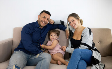 parents playing with their daughter on the sofa at home very happy and fun
