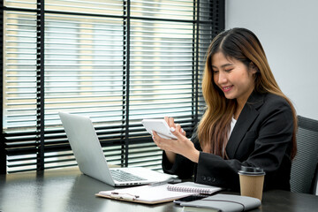 Smiling young manager working on promising project with help of laptop while sitting at modern office.