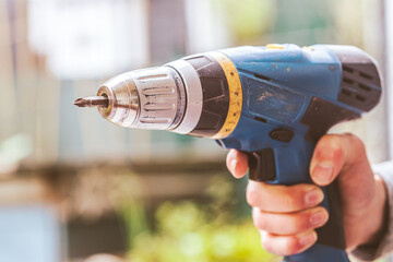 Do it yourself: Home Handyman is holding a cordless screwdriver, outdoors