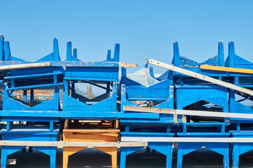 Pile of stacked beach blue white and yellow wooden sunbeds sun beds sun loungers summer season...