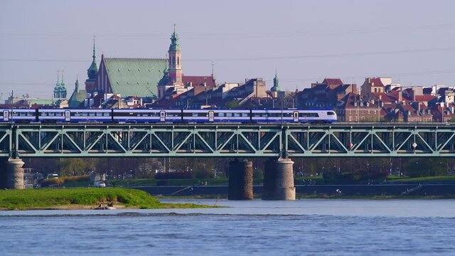 Panorama Warszawy w słoneczny dzień znad Wisły z okolic Żerania. Pociąg na moście kolejowym