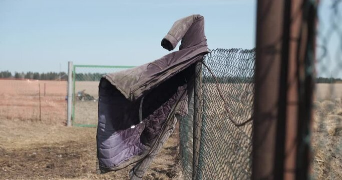 old jacket hangs on the fence and dangles in the wind